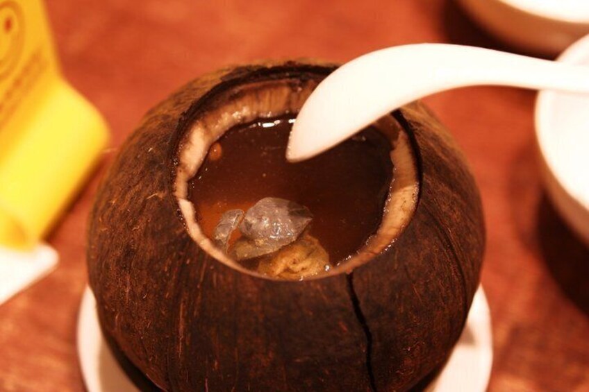 A coconut with a spoon inside it, placed on a white plate. 1