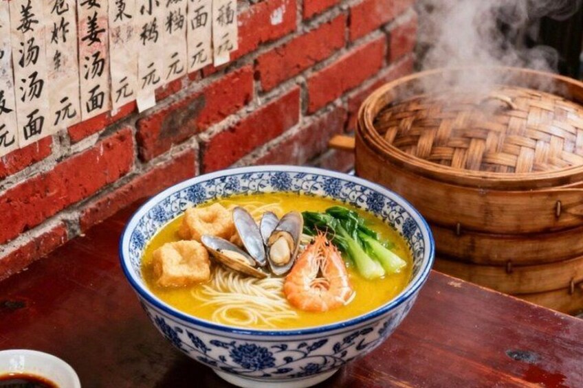 A bowl of soup with seafood, vegetables, and tofu, served in a blue and white bowl, with a brick wall and a bamboo steamer in the background. 3