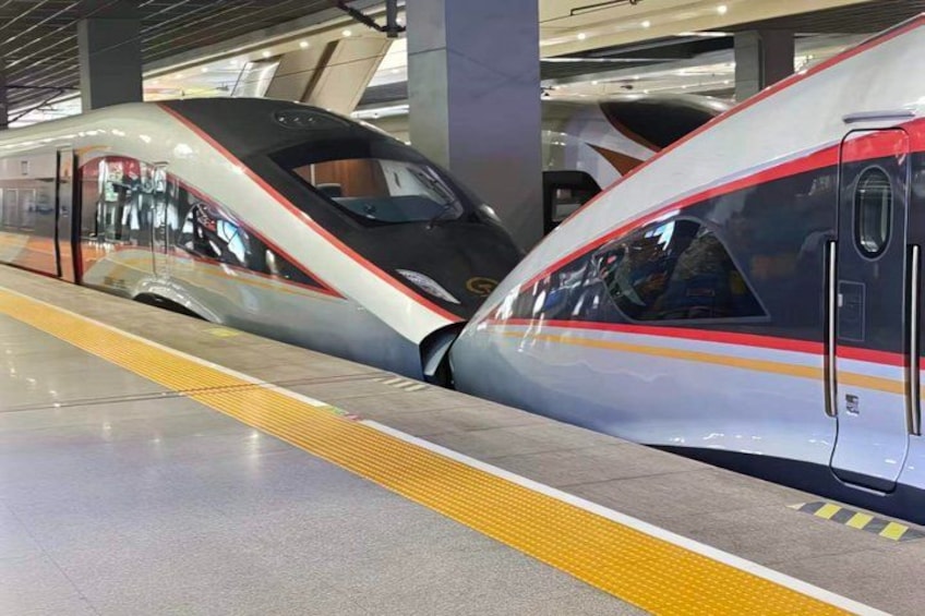 A modern train station with sleek, silver trains and a yellow tactile paving strip. 2