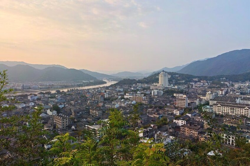 A cityscape with a river, mountains, and a mix of modern and traditional buildings. 3