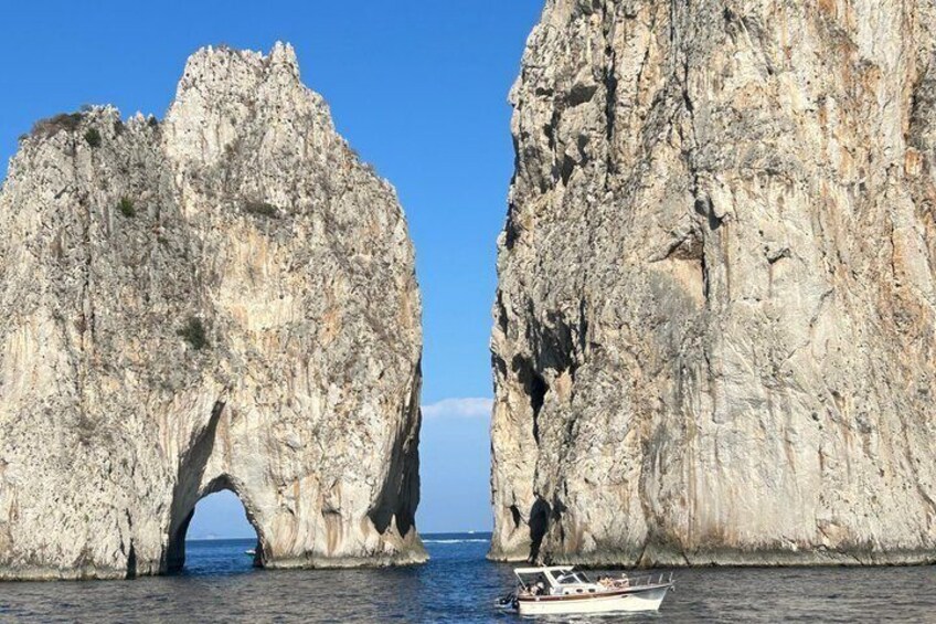 A boat near a rock formation with a natural arch. 1