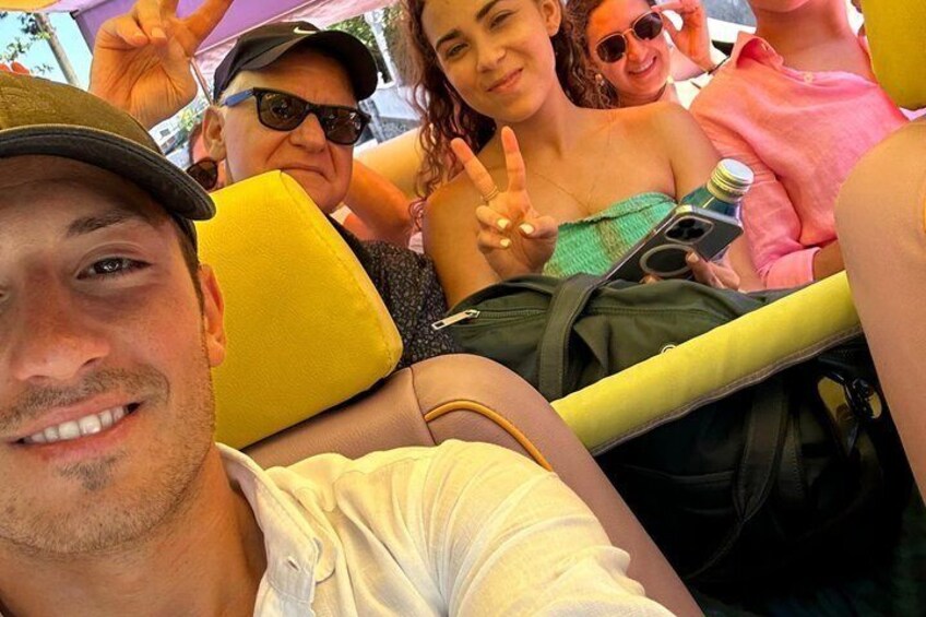 A group of people on a yellow bus with a man in a white shirt and a woman in a green top. 4
