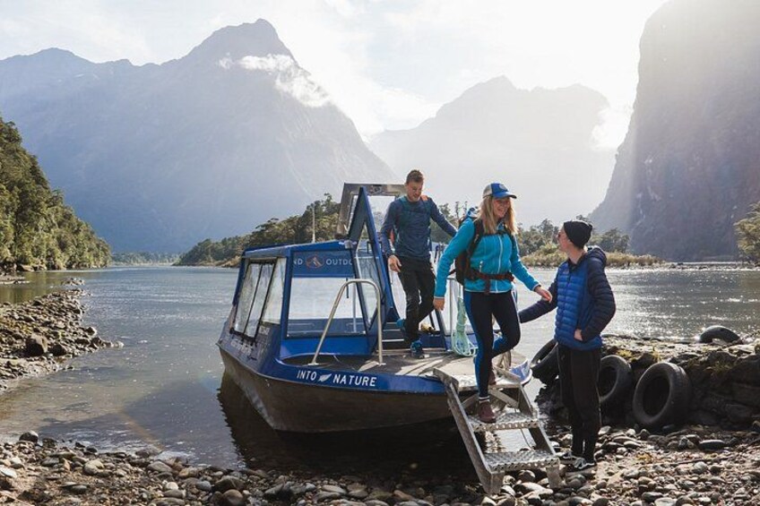 A boat named 'INTO NATURE' docked at a riverbank with people boarding. 4