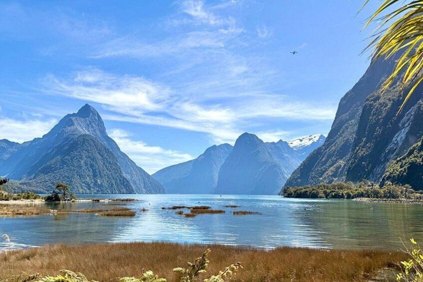 A mountainous landscape with a lake, clear skies, and a distant airplane. 2