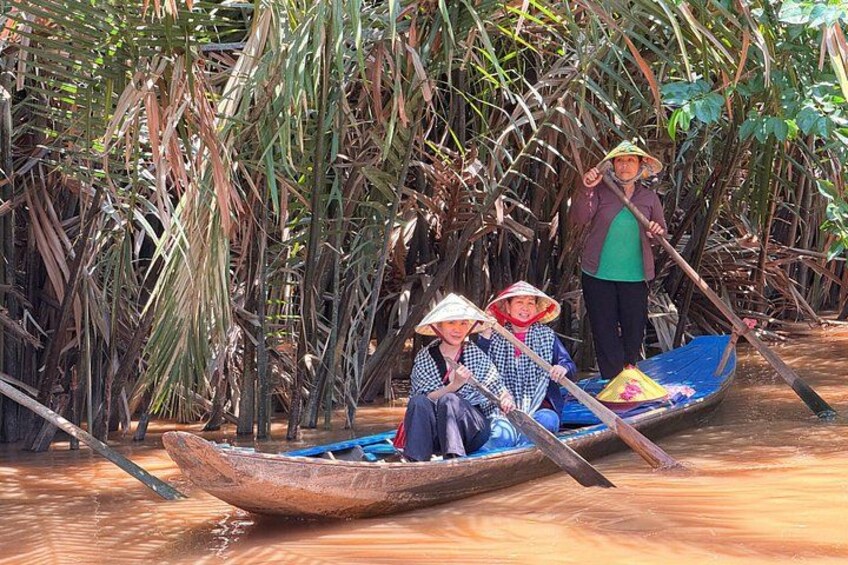 Two people in a boat navigating through a mangrove forest. 4
