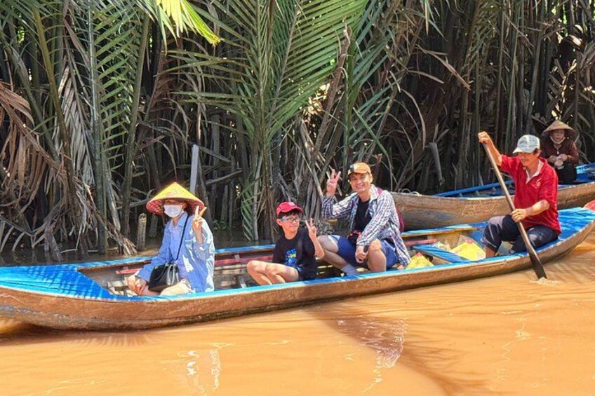 A group of people in a long wooden boat on a river, surrounded by dense tropical vegetation. 3