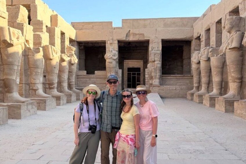 A group of people in an ancient Egyptian temple courtyard with stone columns and statues. 2