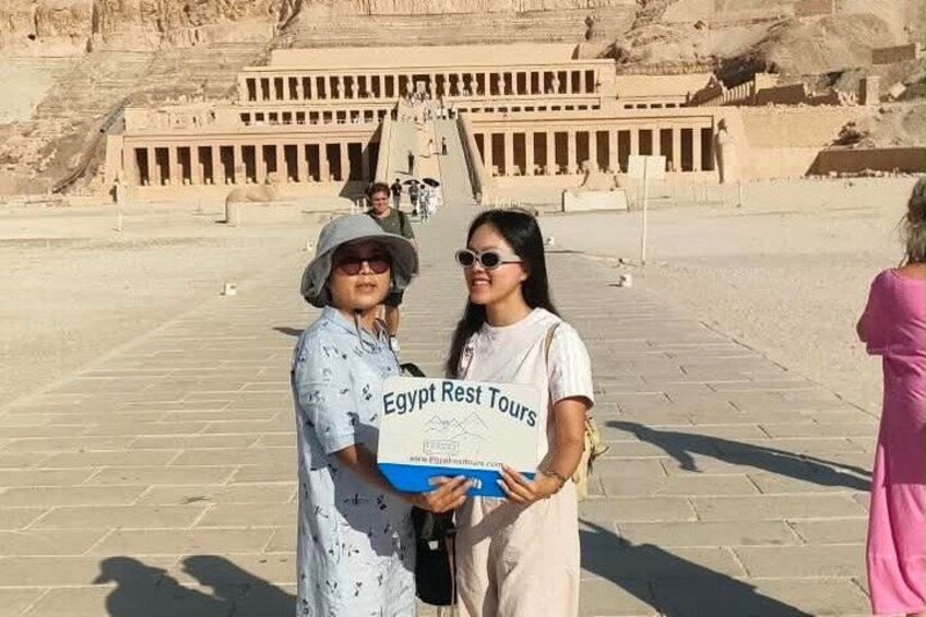 Two people standing in front of a large ancient Egyptian temple with hieroglyphics. 4