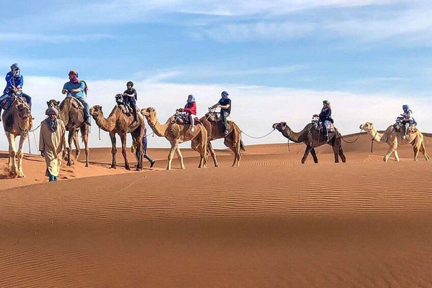 A group of people riding camels across a desert landscape. 5