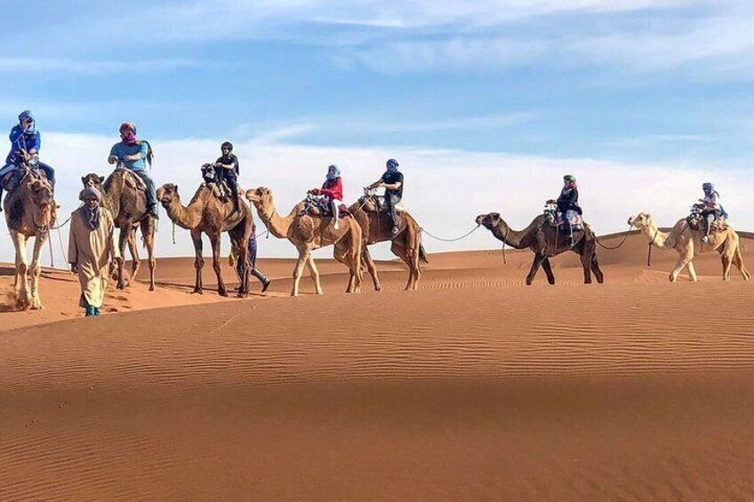 A group of people riding camels across a desert landscape. 5