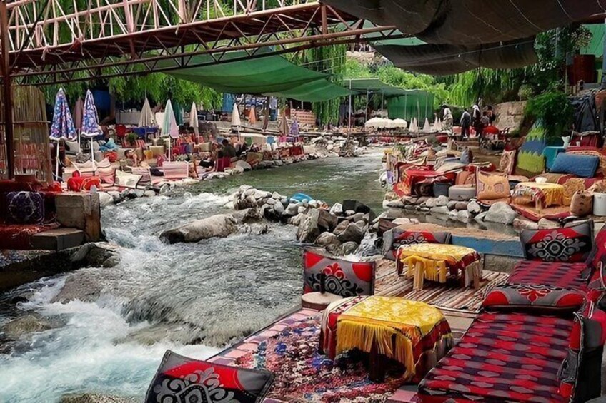 A riverside market with stalls and seating along the water. 4