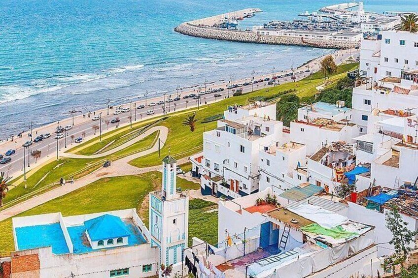 A coastal town with white buildings, a marina, and a clear blue sea. 2