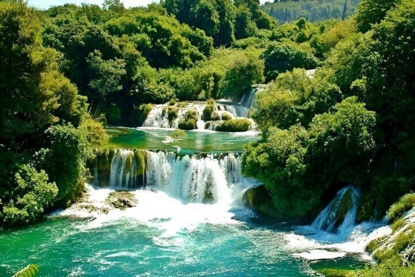 A multi-tiered waterfall surrounded by dense green forest. 1