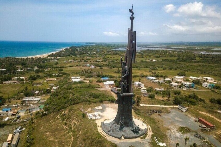 A statue on a pedestal with a coastal background. 2