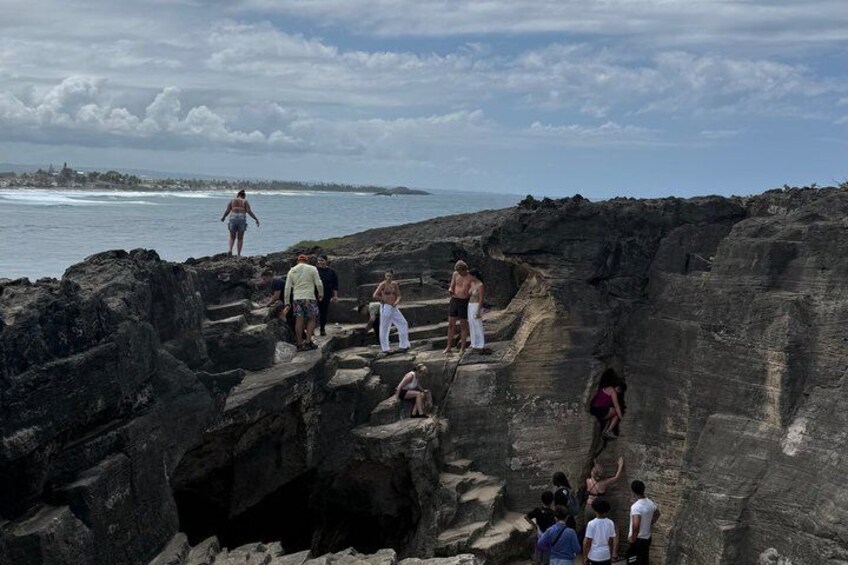 A group of people exploring a rocky coastal area with a view of the ocean. 1