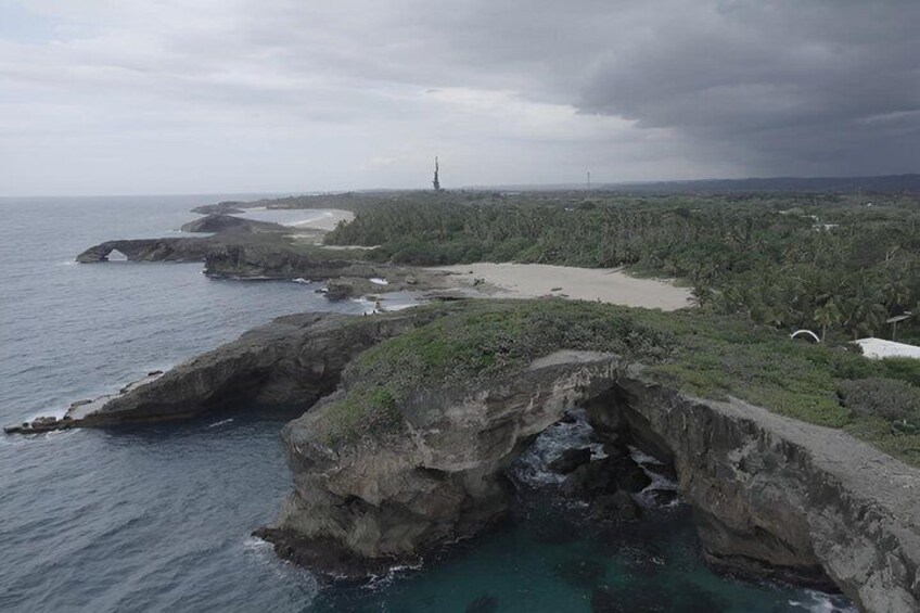 A coastal landscape with rocky cliffs, a lighthouse, and a beach. 5