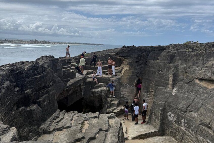 A rocky coastal area with people walking and standing on the cliffs. 2