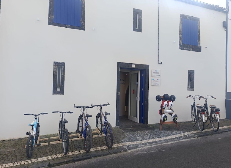 A building with numbered windows and a door, bicycles parked outside, and helmets on a stand. 5