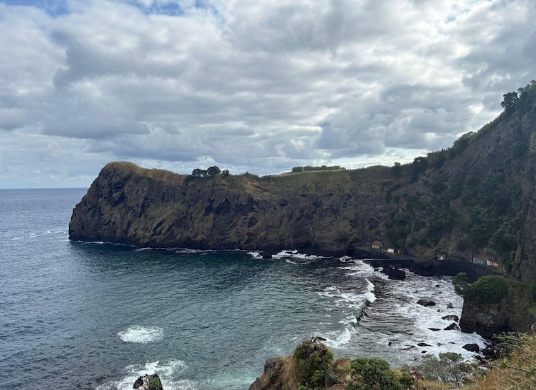 A rugged coastline with a prominent cliff, ocean waves, and a small settlement. 4