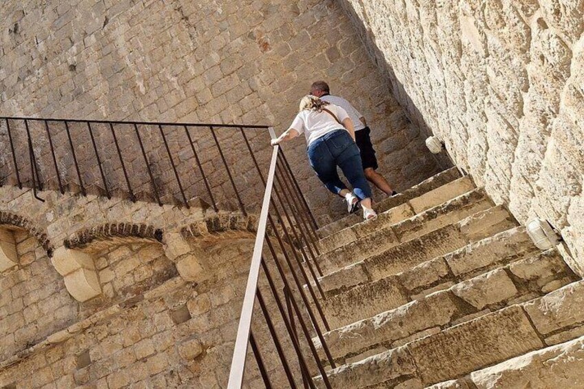 A person descending a stone staircase with a metal railing. 2