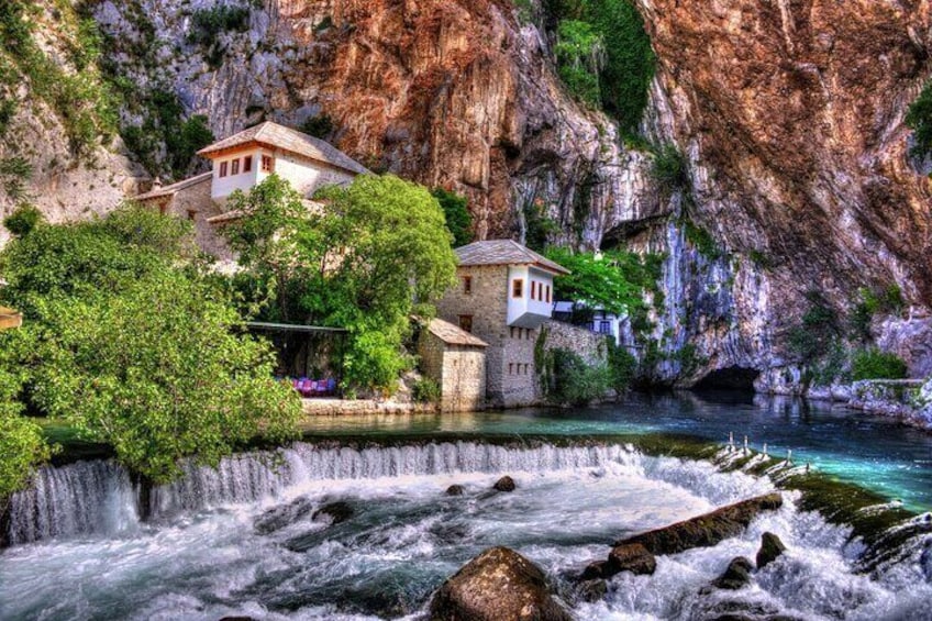 A river with a waterfall, a stone house, and a building with a red roof near the water. 3
