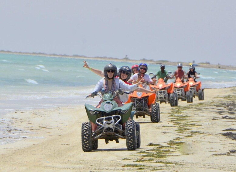A group of people riding ATVs along a beach. 1