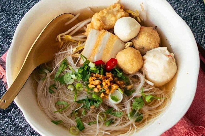 A bowl of noodle soup with various toppings including tofu, boiled eggs, and green onions. 2