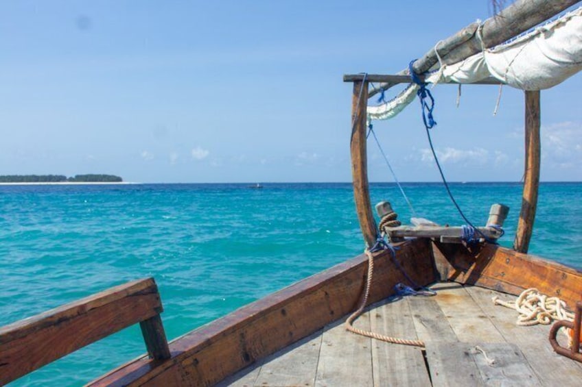 A wooden boat with ropes and a canopy, set against a turquoise sea with a distant island. 2