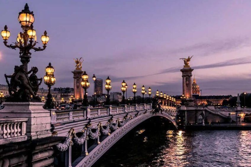 A bridge with ornate lamp posts and statues, reflecting on the water at dusk. 2
