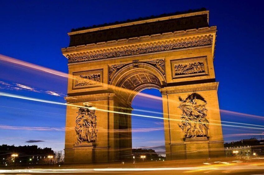 The Arc de Triomphe at night with light trails from passing vehicles. 1
