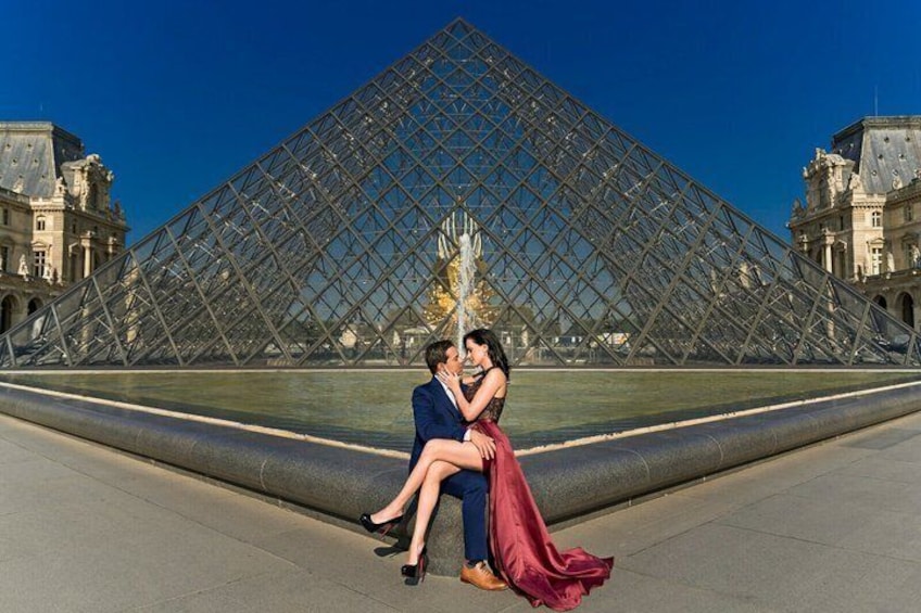 A couple sitting in front of the Louvre Pyramid. 4