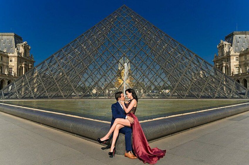 A couple sitting in front of the Louvre Pyramid. 3