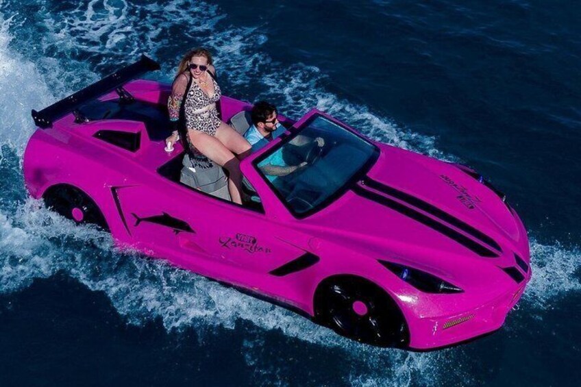 A bright pink jet ski with two people on it, moving through the water. 2
