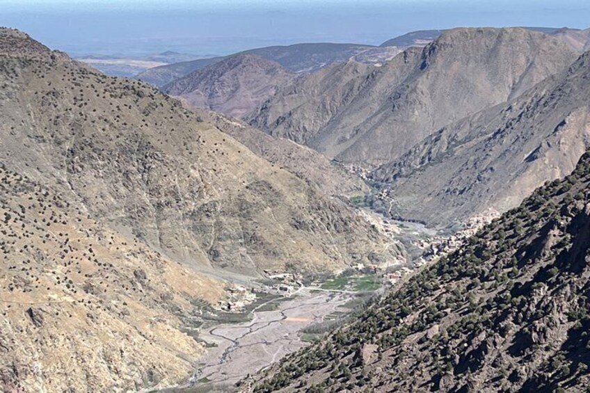 A rugged mountainous landscape with a valley and a small settlement. 1