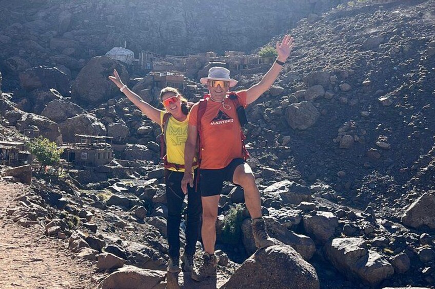 Two people hiking on a rocky trail with a mountainous landscape in the background. 2