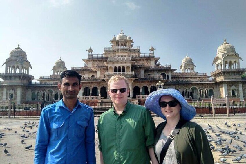 Three people standing in front of a historic building with domes and arches. 1