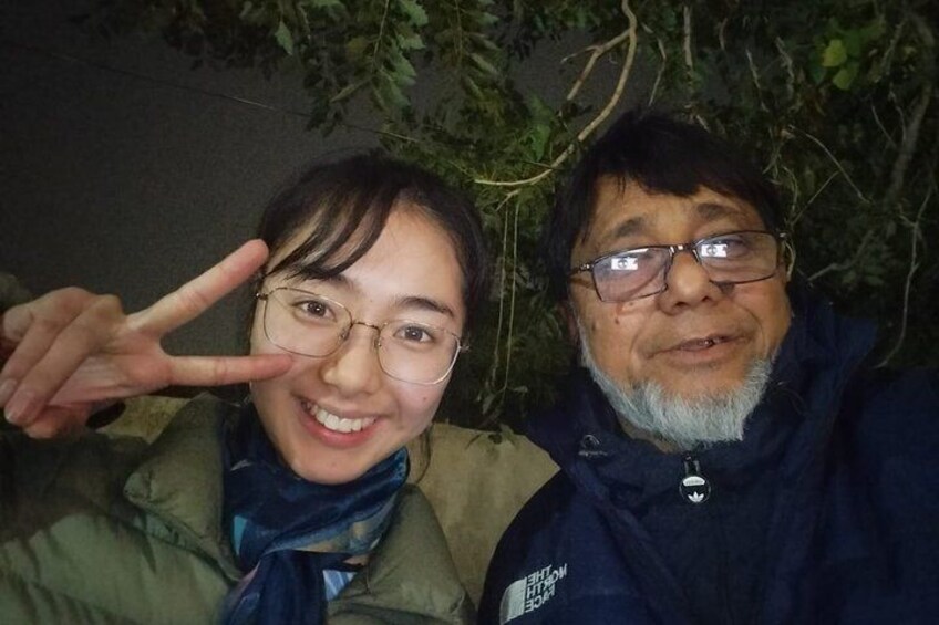 Two people outdoors, one making a peace sign, with a tree in the background. 5