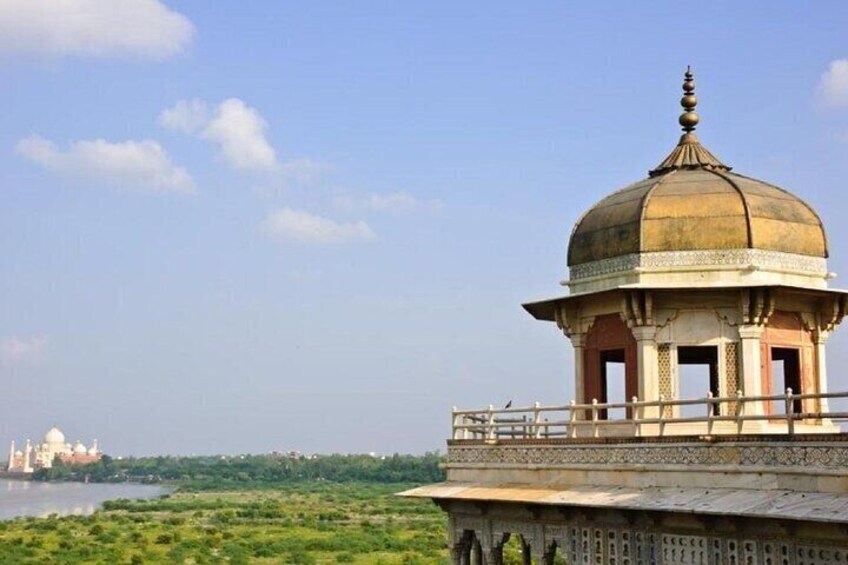 A domed structure with a balcony, a river, and a distant fort. 3