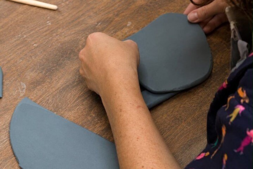 A person working with a flat, grey object on a wooden surface. 3