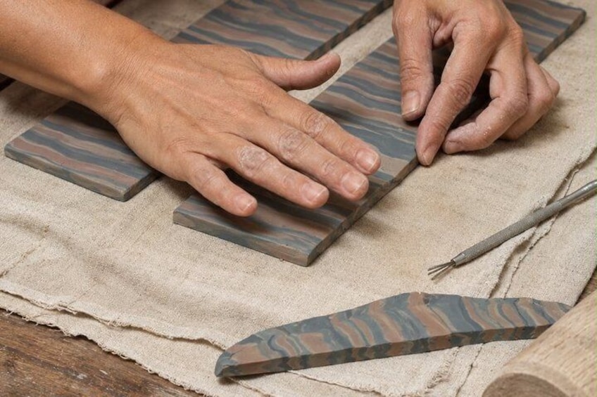 Hands working with rectangular stone slabs on a fabric surface. 4