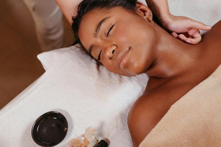 A person lying down with a towel, a bowl, and a flower on a table. 4