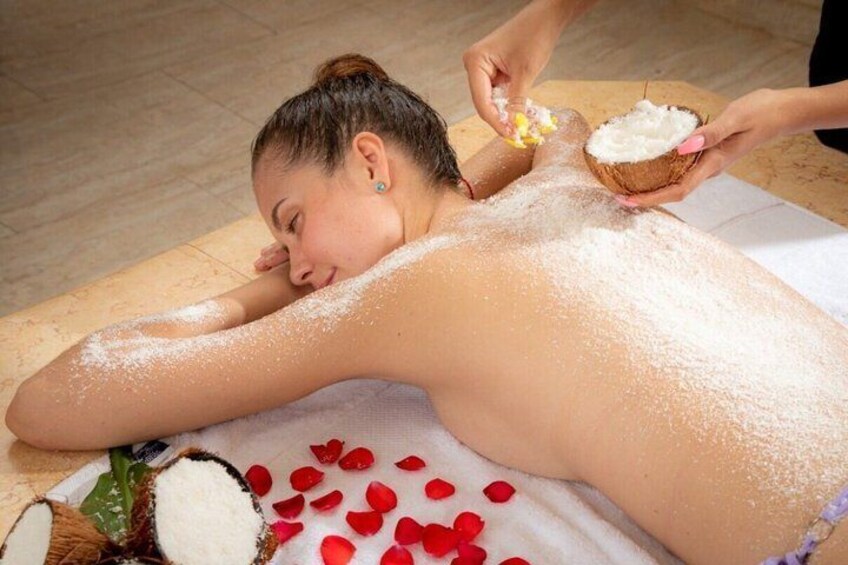 A person receiving a back treatment with coconut powder and rose petals. 2