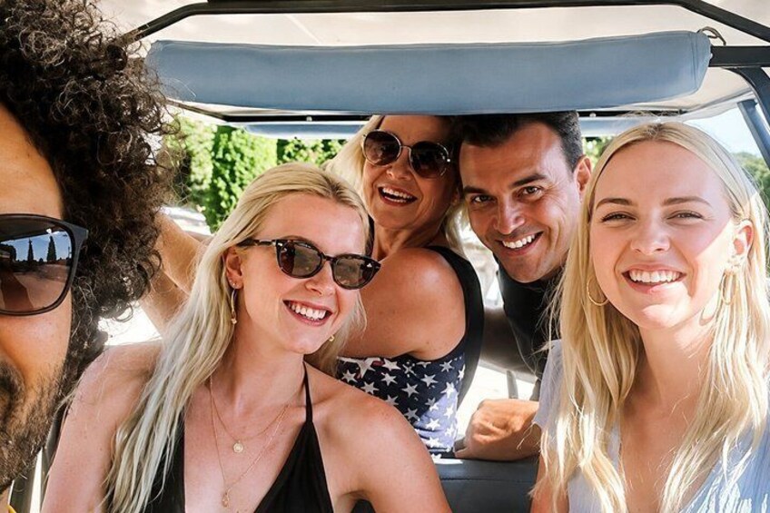 A group of people in a convertible with a sunroof, parked outdoors. 4