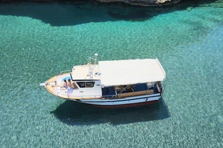 A boat with a white canopy and blue trim floating on clear turquoise water. 4