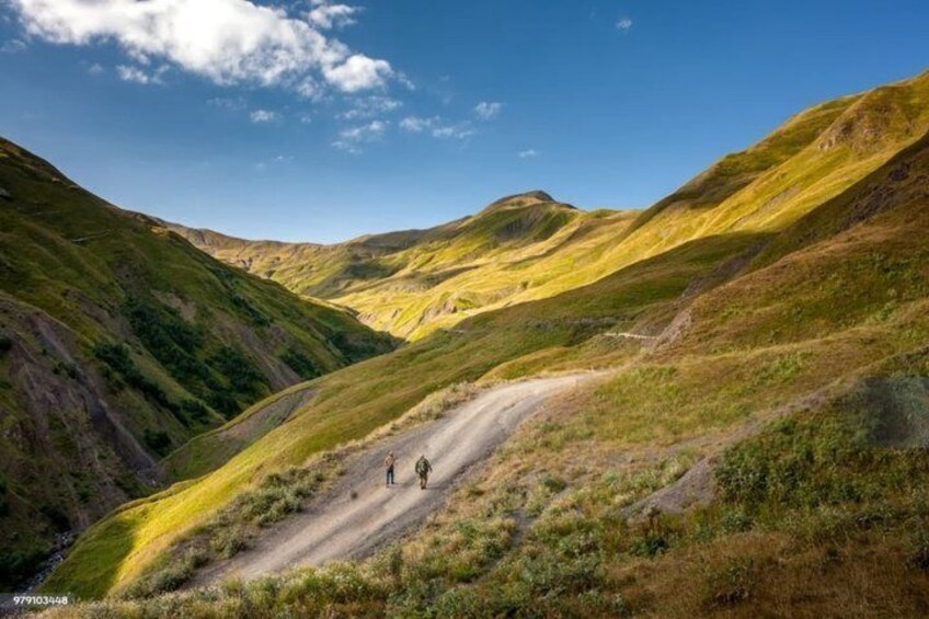 A winding mountain road with two hikers. 3
