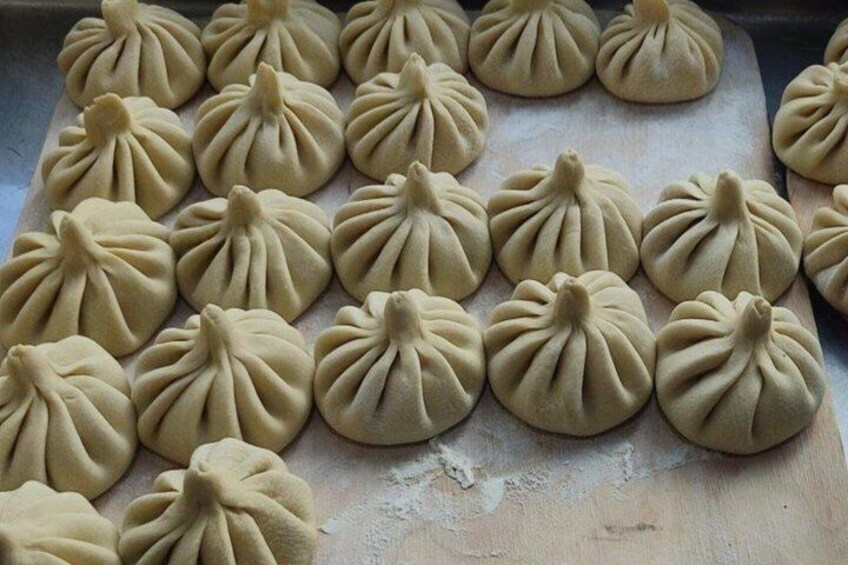 A tray of uniformly shaped dumplings arranged in rows. 5