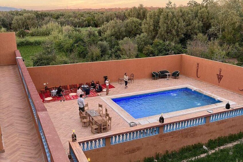 A rooftop pool with people around it, surrounded by greenery. 1