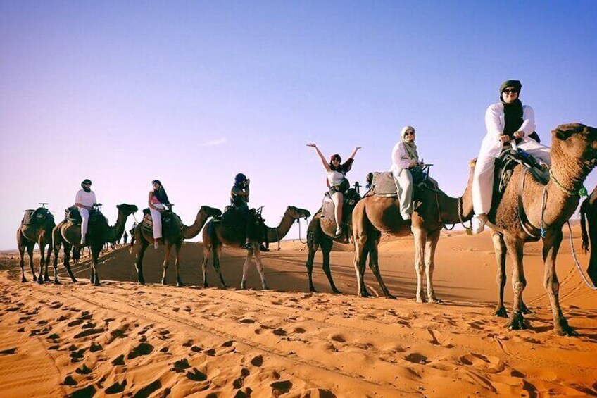 A group of people riding camels in a desert. 5