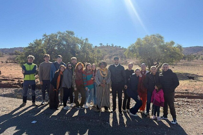 A group of people standing outdoors in a dry, open landscape with sparse vegetation and a clear sky. 3