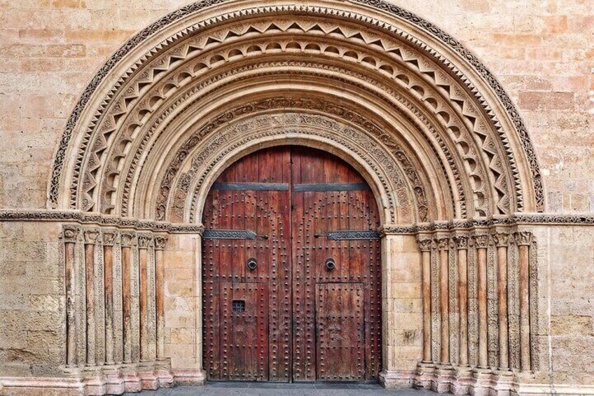 A large, ornate wooden door with intricate carvings and a stone archway. 5